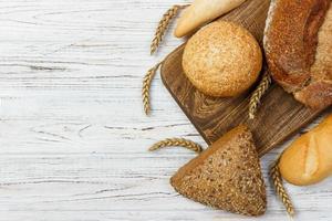 Bread and wheat on white wooden background photo