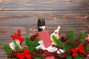 Top view of flatware tied up with ribbon on napkin on wooden background. Christmas decorations and reindeer with empty space for your design. New Year holiday concept photo