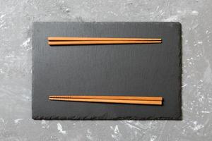 rectangular slate plate with chopsticks for sushi on black marble background photo