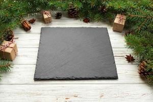 Perspective view. Empty black slate square plate on wooden christmas background. holiday dinner dish concept with new year decor photo