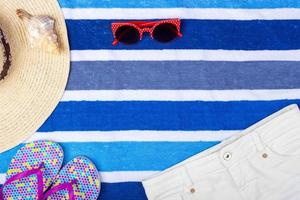 Straw Beach Woman's Hat Sun Glasses Top View Seashell Shorts Flip flops with space for text. photo