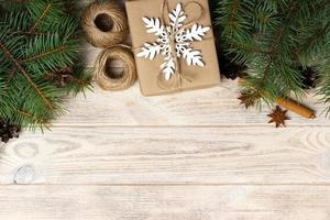Christmas decoration elements string, chrtistmas tree branches with cones and several decorated gifts on white wooden background photo