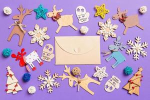 Festive decorations and toys on purple background. Top view of craft envelope. Merry Christmas concept photo