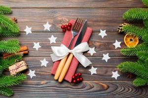 Top view of utensils on festive napkin on wooden background. Christmas decorations with dried fruits and cinnamon. Close up of New year dinner concept photo