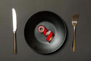 Healthy diet concept of plate with measuring tape, fork and knife on black background. Top view photo