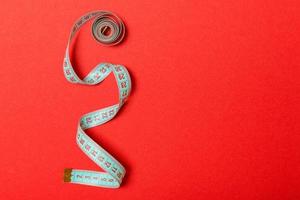 Tangled measuring tape with space for your idea. Sewing and tailor concept on red background photo