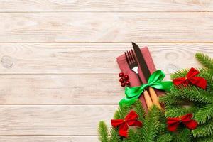 Top view of christmas decorations on wooden background. Fork and knife on napkin tied up with ribbon and empty space for your design. New year pattern concept photo