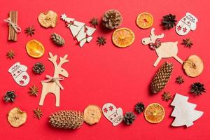 Top view of red background decorated with festive toys and Christmas symbols reindeers and New Year trees. Holiday concept with copy space photo