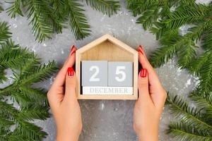 Female hands hold the Christmas calendar, 25 december on grey cement table with decoration photo