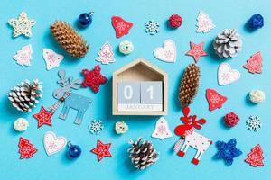 Top view of wooden calendar surrounded with New Year toys and decorations on blue background. The first of January. Christmas time concept photo