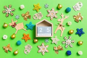 Top view of wooden calendar on green background with New Year toys and decorations. The twenty fifth of December. Christmas time concept photo