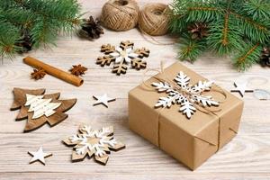 gift box in craft paper with Christmas decoration, twine rope, concept background, top view on wood table surface. Christmas ornaments and presents border with snowflakes and stars photo