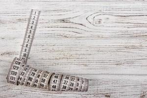 Close up tailor measuring tape on wooden table background. White measuring tape shallow dept of field photo