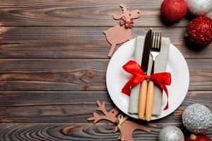 Holiday composition of Christmas dinner on wooden background. Top view of plate, utensil and festive decorations. New Year Advent concept with copy space photo