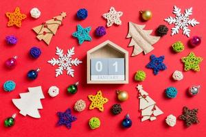 vista superior del calendario sobre fondo rojo hecho de decoraciones navideñas y juguetes. concepto de adorno de navidad foto