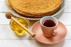 Hot pancakes with honey on a plate, Breakfast tea with crepes photo