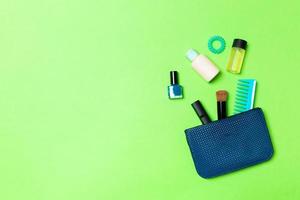 Make up products spilling out of cosmetics bag on green background with empty space for your design photo