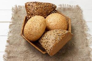 Bread rolls in the basket on rustic wooden background photo