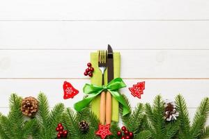 Top view of christmas decorations on wooden background. Fork and knife on napkin tied up with ribbon and empty space for your design. New year pattern concept photo
