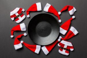 Festive set of plate decorated with Santa Claus hat on colorful background. Top view christmas dinner concept photo