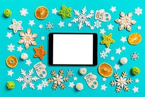 Top view of digital tablet on blue background with New Year toys and decorations. Christmas time concept photo