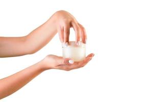 mano femenina sosteniendo una botella de crema de loción aislada. Chica abriendo tarro de productos cosméticos sobre fondo blanco. foto