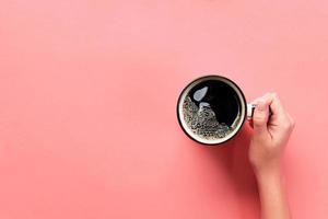 High angle of woman hands holding coffee mug on pink background Minimalistic style. Flat lay, top view isolated photo