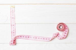 Frame made of measuring tape on wooden background. Top view of sewing concept. Slim waist concept with empty space for your design photo