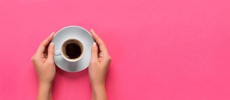 alto ángulo de manos de mujer sosteniendo una taza de café sobre fondo rosa estilo minimalista. banner plano de vista superior con espacio de copia para su diseño aislado foto