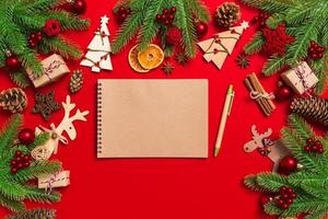 Top view of notebook on red background made of Christmas decorations. New Year time concept photo