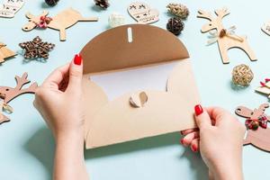 Top view of woman holding an envelope on blue background made of holiday decorations. Christmas time concept photo