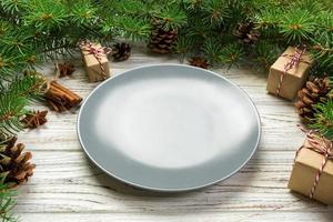 vista de perspectiva. plato vacío de cerámica redonda sobre fondo de navidad de madera. concepto de plato de cena navideña con decoración de año nuevo foto