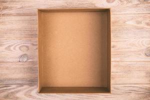 Opened cardboard box on wooden background. vintage, toned top view photo