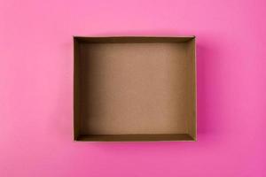 empty cardboard paper box on pink background. delivery concept, top view photo