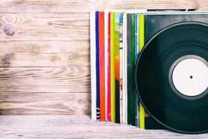 Retro styled image of a collection of old vinyl record lp's with sleeves on a wooden background with Copy space toned photo