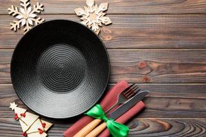 Top view of plate, fork and knife served on Christmas decorated wooden background. New Year Eve concept with copy space photo