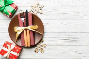 Top view of plate, fork and knife served on Christmas decorated wooden background. New Year Eve concept with copy space photo