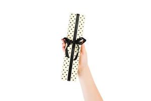 Woman hands give wrapped Christmas or other holiday handmade present in yellow paper with black ribbon. Isolated on white background, top view. thanksgiving Gift box concept photo