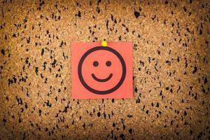 red paper with smiling face on corkboard. bulletin board. photo