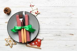 Holiday composition of Christmas dinner on wooden background. Top view of plate, utensil and festive decorations. New Year Advent concept with copy space photo