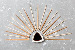 Many bamboo chopsticks with soy sauce on black cement stone background, top view with copy space. a lot of sushi sticks in the form of an ornament photo