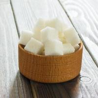 cubos de azúcar en un tazón sobre una mesa de madera. terrones de azúcar blanca en un tazón foto