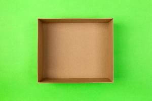 empty cardboard paper box on green background. delivery concept, top view photo