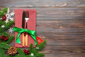 Top view of christmas decorations on wooden background. Fork and knife on napkin tied up with ribbon and empty space for your design. New year pattern concept photo