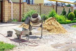 máquina mezcladora de cemento en el sitio de construcción, herramientas y arena foto