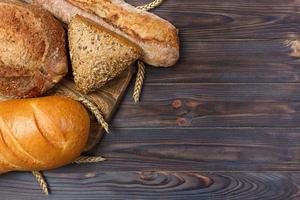 Homemade loaf of wheat bread baked on wooden background. top view with copy space photo
