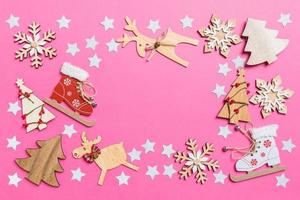 Top view of pink background decorated with festive toys and Christmas symbols reindeers and New Year trees. Holiday concept with copy space photo