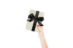 Woman hands give wrapped Christmas or other holiday handmade present in yellow paper with black ribbon. Isolated on white background, top view. thanksgiving Gift box concept photo