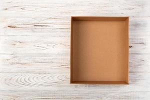 Opened brown blank cardboard box on wooden background, top view photo