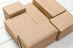 paquete de correo marrón paquete en blanco para su diseño. caja de cartón sobre un fondo de madera foto